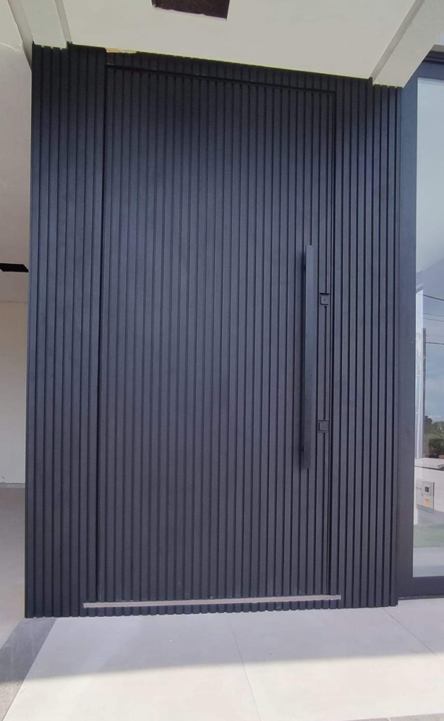 Portão de acabamento escuro com fechamento vertical.